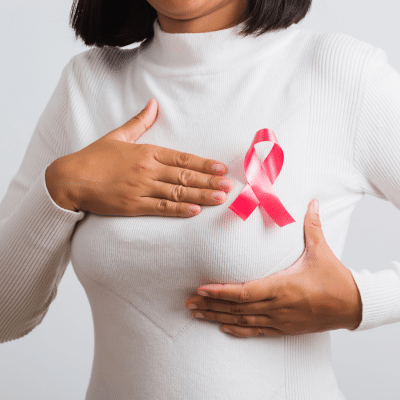 Woman holding breast with breast cancer pin attached to shirt, representing breast health