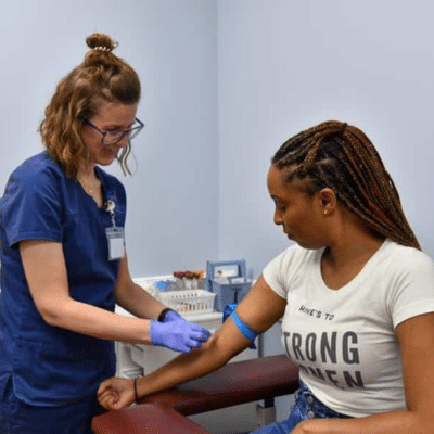 A woman in blue scrubs getting blood shot, representing womens health care in lynchburg va