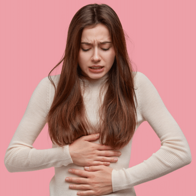 A woman holding her stomach, representing common causes of pelvic pain
